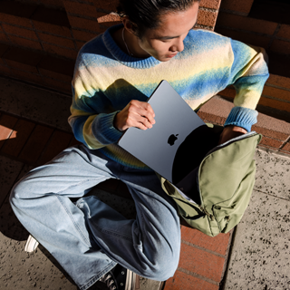 Vorderansicht einer Person, die ein zugeklapptes 15" MacBook Air in eine Tasche steckt